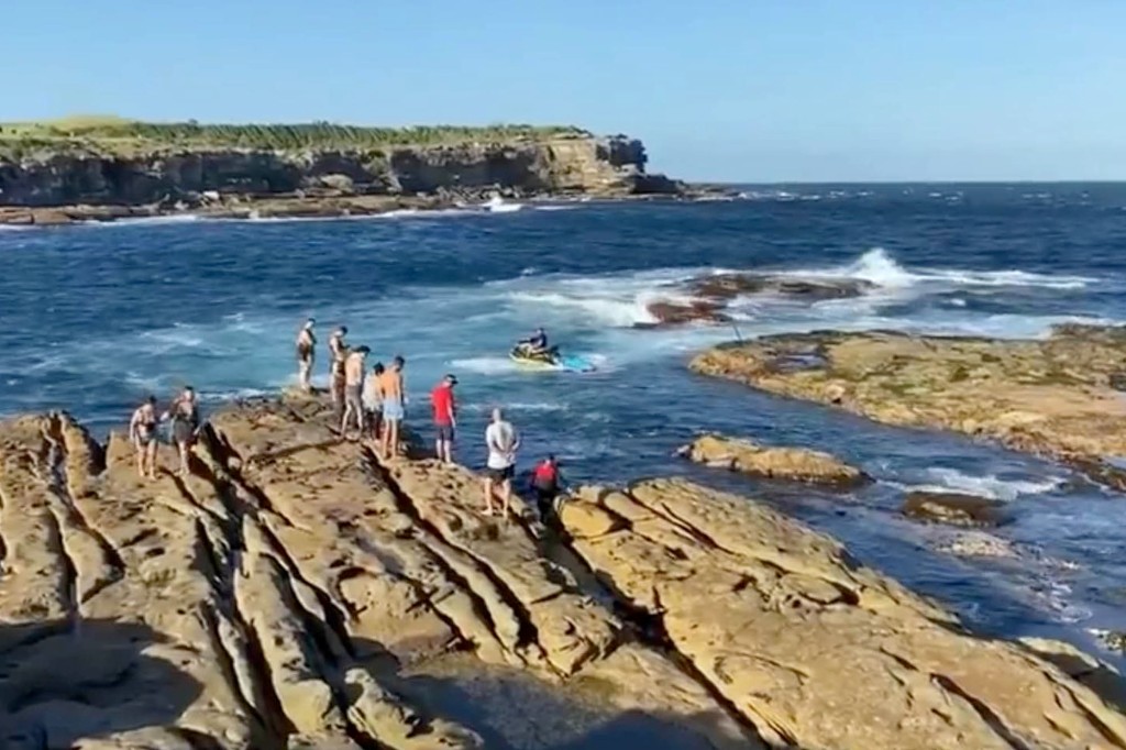 Menschen in der Nähe des Ozeans schauen auf den Schwimmer, der von einem Weißen Hai gefressen wurde, als die Behörden den Menschen befahlen, sich vom Wasser fernzuhalten.