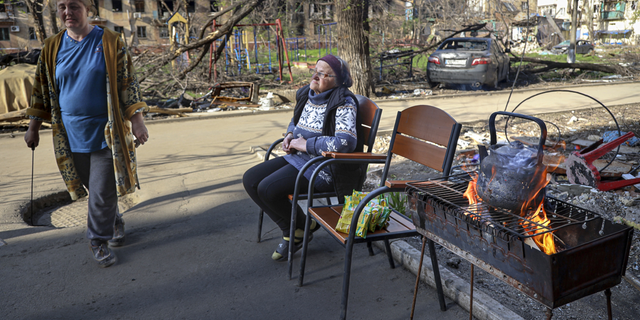 Einheimische Frauen versammeln sich am Dienstag, den 26. April, am Eingang eines zerstörten Wohnhauses in Mariupol, Ukraine.
