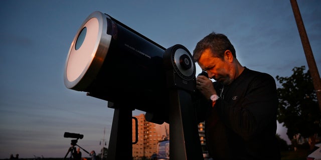 Robert Burgess, Chefastronom für Süd-Maine, stellt ein Teleskop mit Sonnenfiltern auf, um am Donnerstag, den 10. Juni 2021, eine partielle Sonnenfinsternis von der East Party in Portland aus zu beobachten.